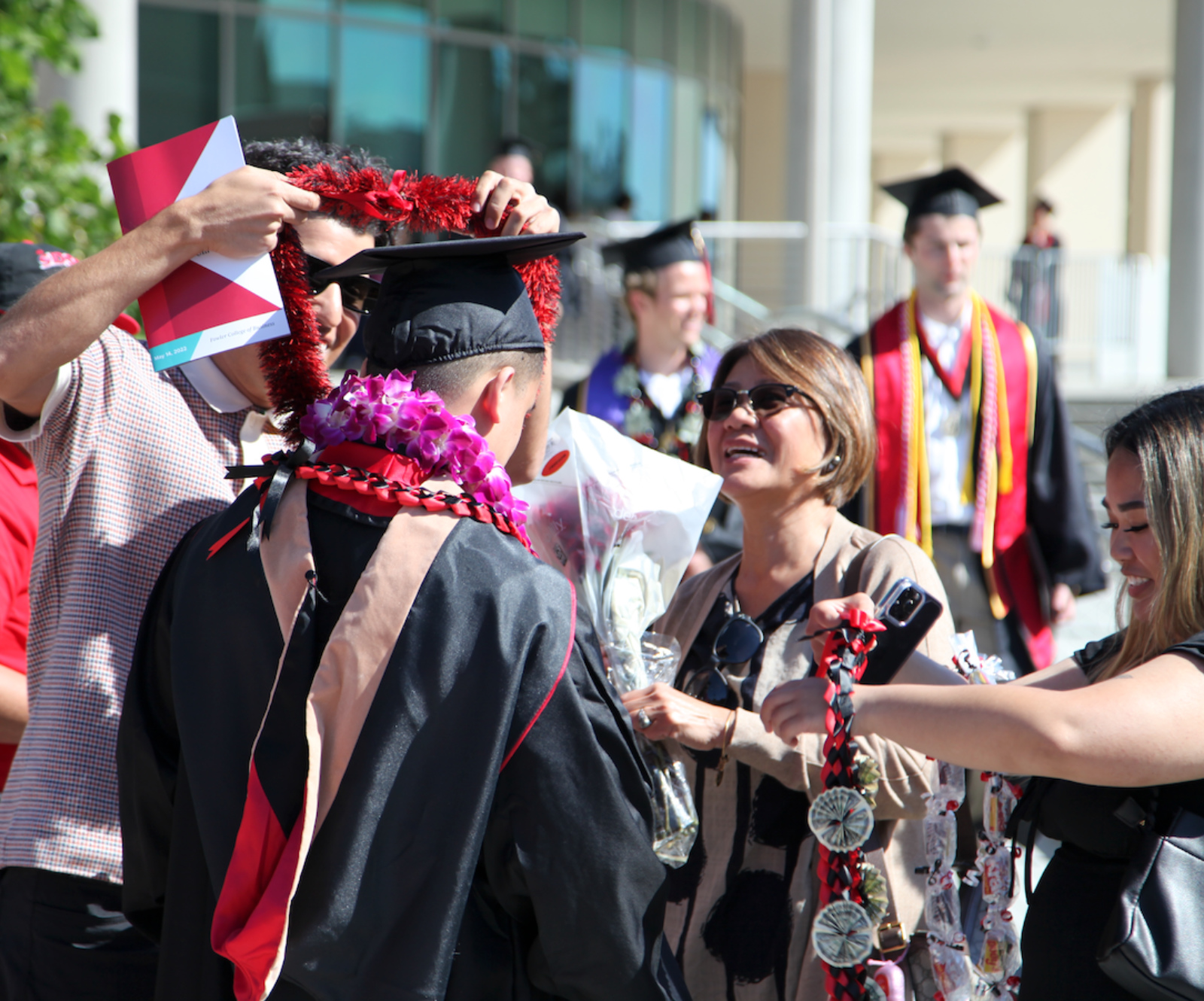 Graduate getting a lei wrapped around them.